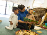 A nursery worker reading a book to a baby at Higher Broughton Nursery
