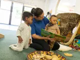 A nursery worker reading a book to a baby at Higher Broughton Nursery