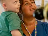 A nursery worker holding a young boy