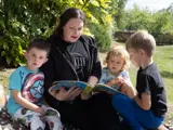 A nursery worker reading a book to some children at Higher Broughton Nursery