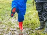 A child in wet gear playing outside at Barton Moss Nursery