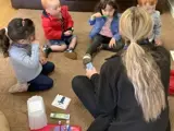 A group of toddlers sat on the floor brushing their teeth