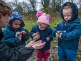 A nursery worker playing outside with some children at Barton Moss Nursery