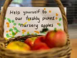 A basket of apples with a note saying: Help yourself to our freshly picked nursery apples